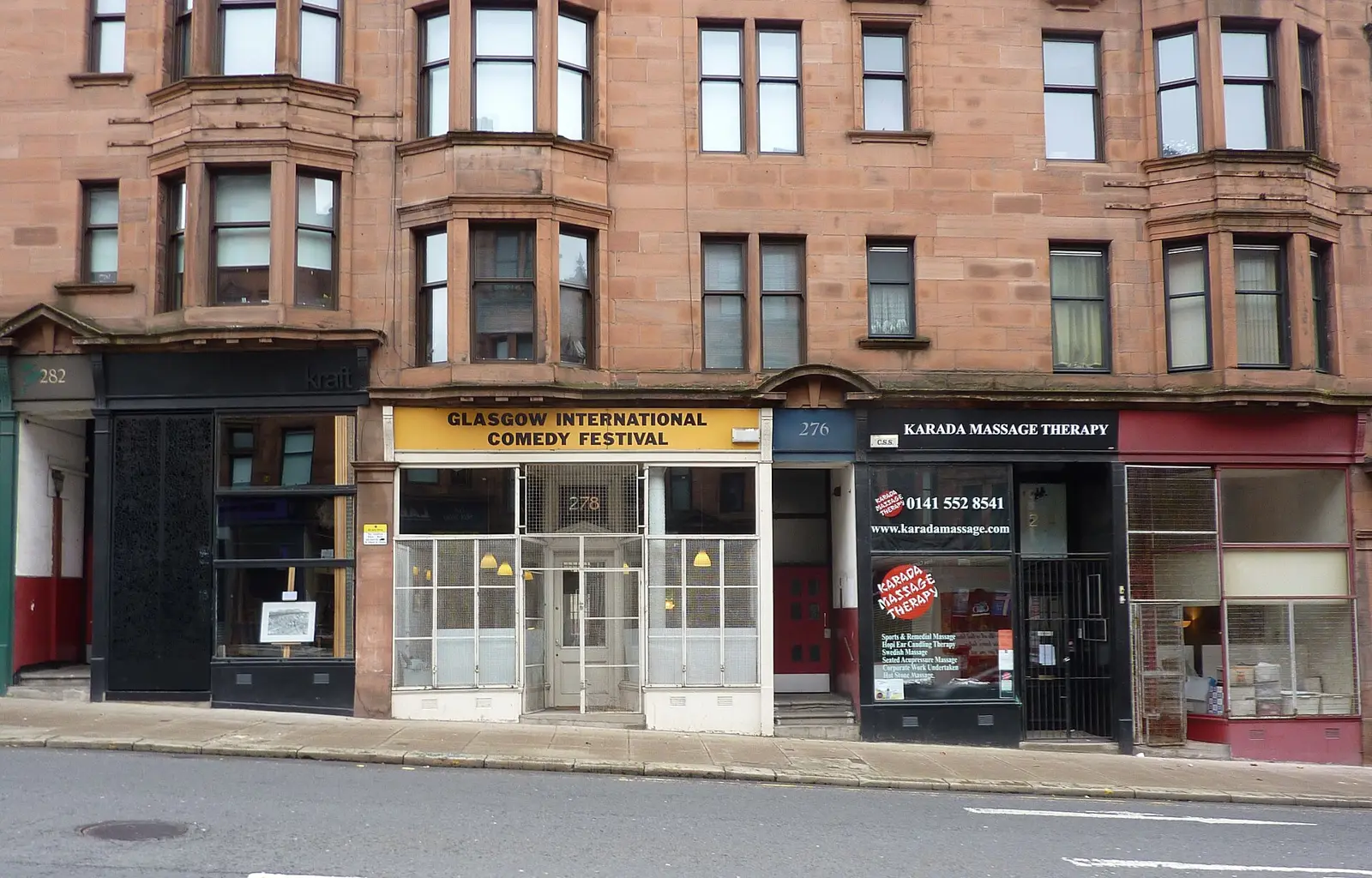 A row of shop fronts below sandstone tenements on a Glasgow high street